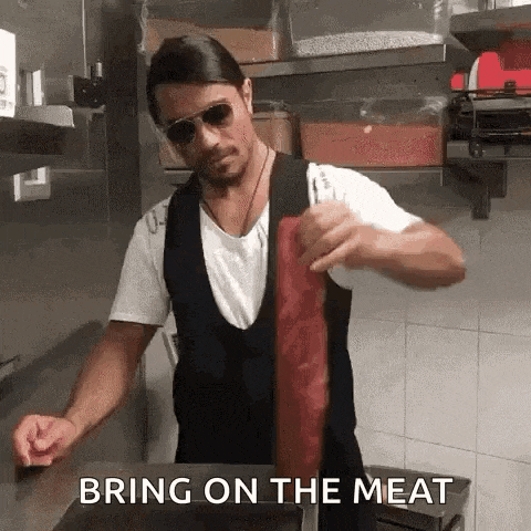 a man in sunglasses is holding a piece of meat in a kitchen and says `` bring on the meat '' .