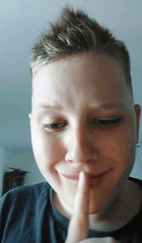 a young man holds his finger to his mouth