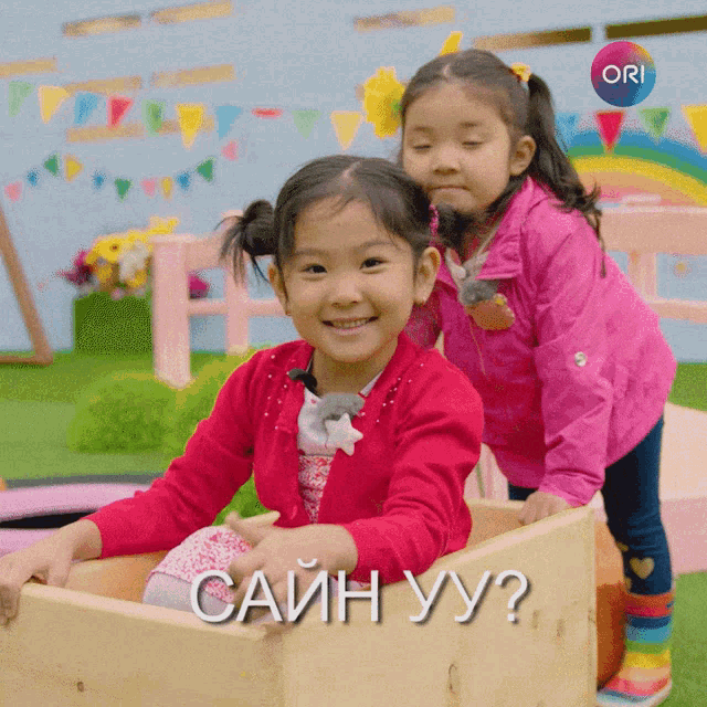 two little girls are playing in a wooden box with the words " cain yy ? " on the bottom