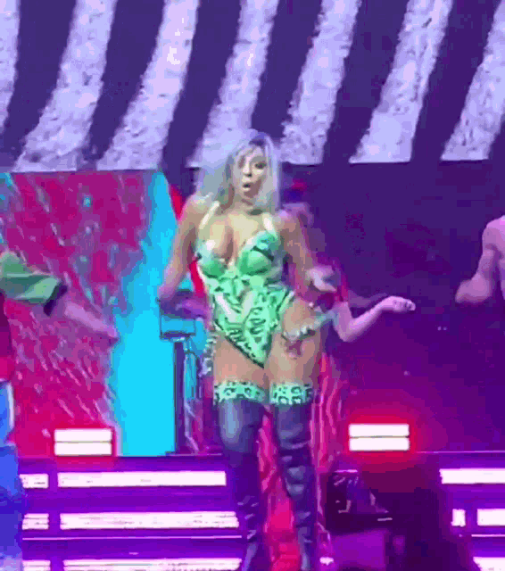 a woman in a green leotard is dancing on a stage