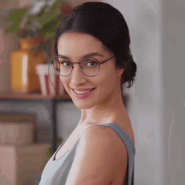 a woman wearing glasses and a blue top smiles for the camera
