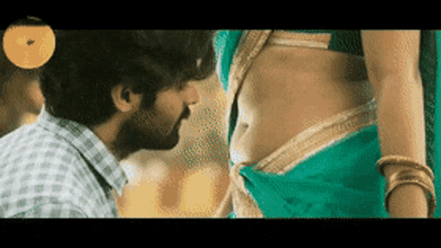 a man is kissing a woman 's belly in a green saree