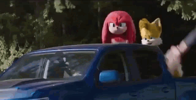 sonic the hedgehog , knuckles the echidna , and tails are sitting in a blue truck .