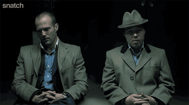 two men sitting next to each other with snatch written on the bottom right