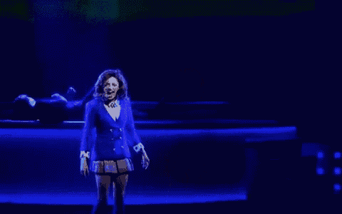 a woman in a blue suit is standing on a stage with a green background .