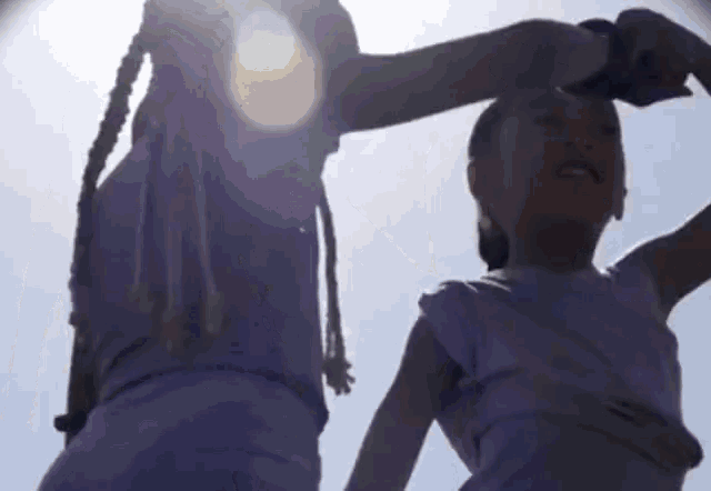 two little girls are holding hands and dancing in the sunlight