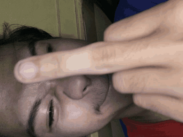 a close up of a person 's face with their fingers on their nose