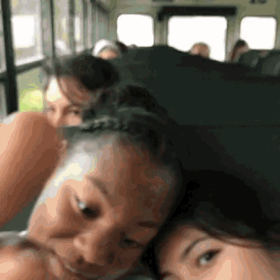 a group of people are sitting on a bus and one of them is looking at the camera