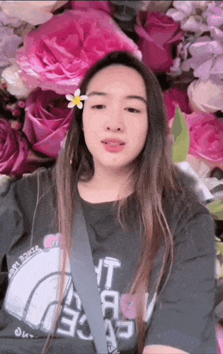 a woman with a flower in her hair is wearing a t-shirt that says " the north face "