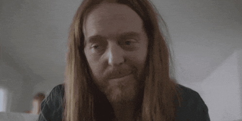 a man with long hair and a beard has the words and for being a complete fuckwit below him