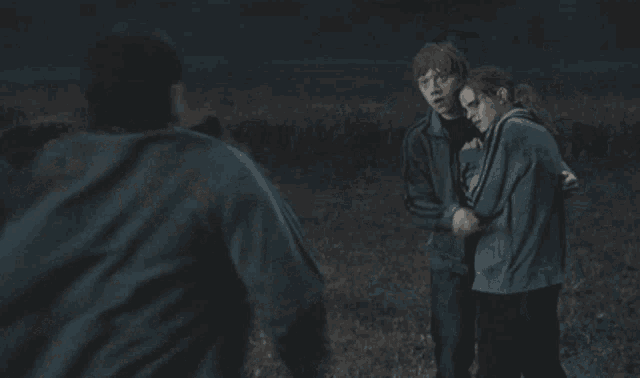 a couple of people hugging each other in a dark field