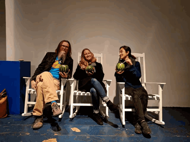 a man and two women sitting in rocking chairs holding watermelons