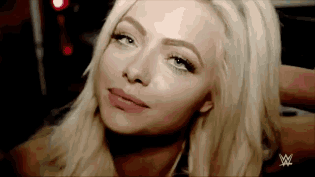 a close up of a woman 's face with a w logo on the bottom right corner .