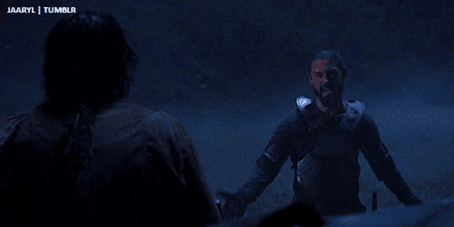 a man with a beard is standing next to a woman in a dark room with the words jaaryl tumblr visible