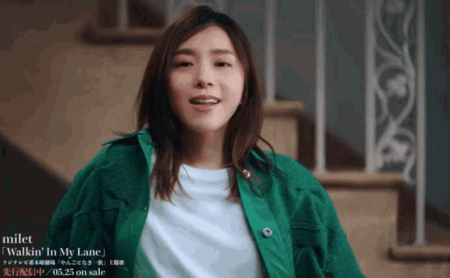a woman in a green jacket stands in front of a set of stairs with the words milet walkin ' in my lane