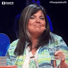 a woman is sitting at a table holding a glass of water and smiling