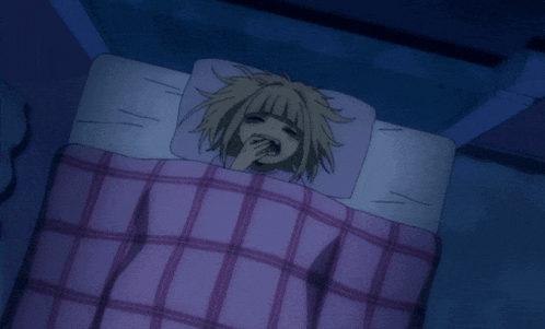 a girl is laying in a bed with a purple blanket