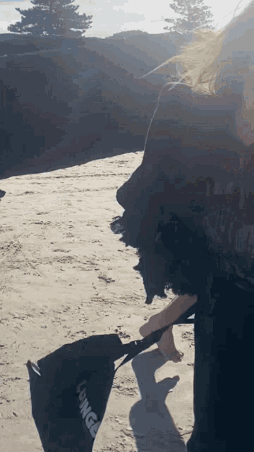 a person standing on a beach with a bag that says fringe on it