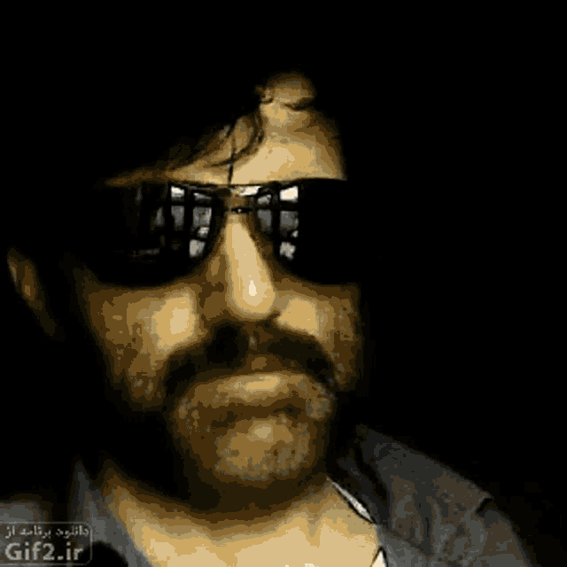 a man with a beard and mustache wearing sunglasses with arabic writing on it