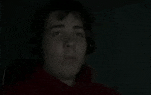 a man is wearing headphones in the dark and looking at something .