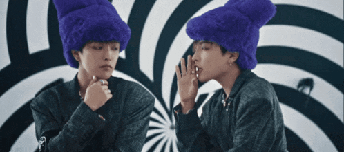 a man in a purple hat looks at himself in the mirror