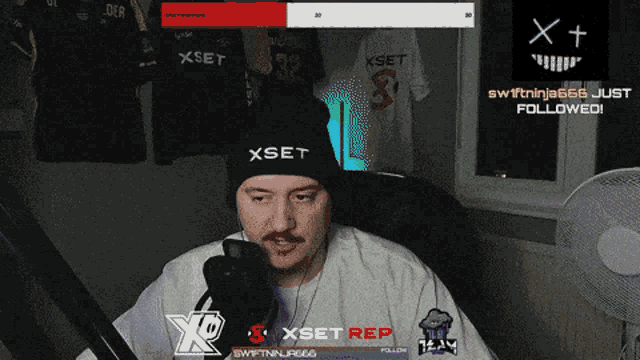 a man wearing a black xset beanie looks at his phone