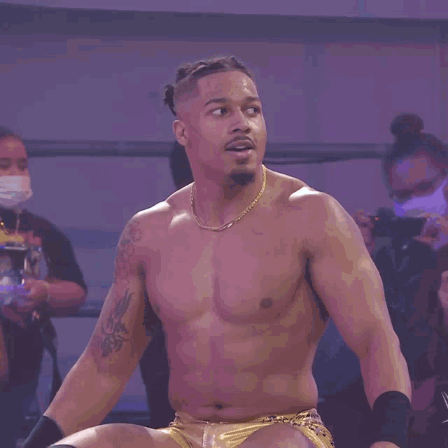 a shirtless wrestler is wearing gold shorts