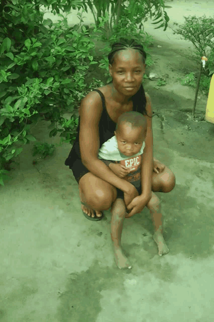 a woman is holding a little boy who is wearing an epic shirt
