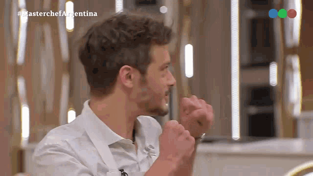 a man 's fist is raised in the air while watching a masterchef argentina show