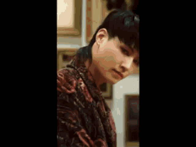 a close up of a young man with a mullet and a floral shirt .