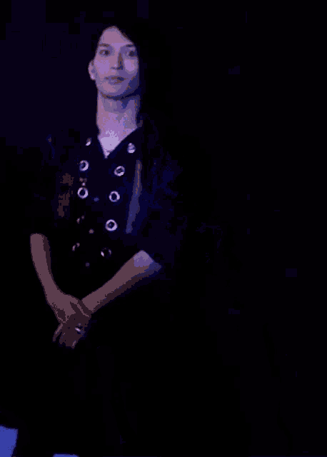 a man is covering his mouth with his hands in a dark room