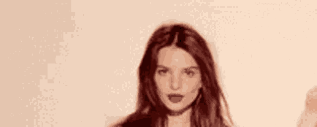 a woman with long hair is standing in front of a white background .