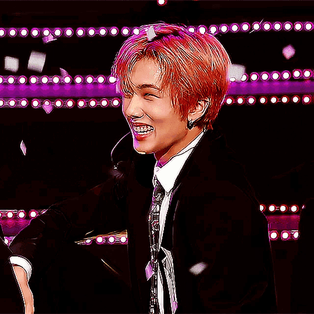 a man with red hair is wearing a black suit and tie and a name tag that says ' nct dream ' on it