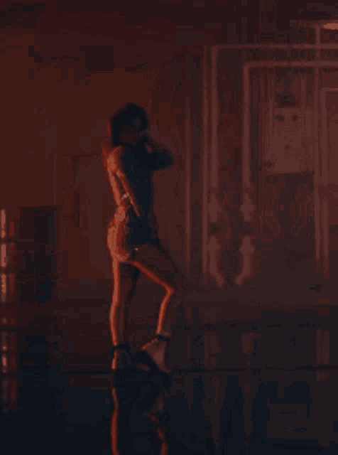 a woman in a white dress is dancing in a dark room with a red light behind her