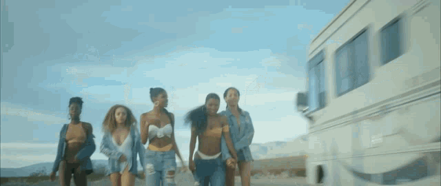 a group of women in bikinis are walking down a road .