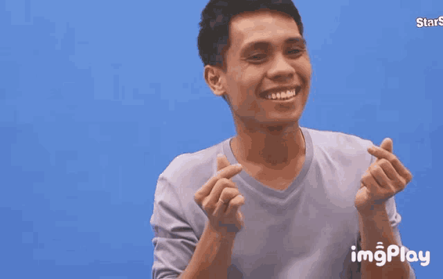 a man is smiling and making a heart with his hands and the words yamyam behind him