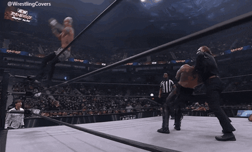 a group of wrestlers are laying on the ground in a wrestling ring while a referee watches