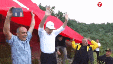 a group of men holding up a large red flag with the number 7 on the bottom