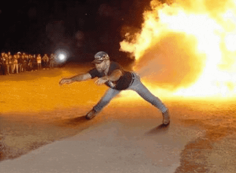 a man is standing in front of a huge fireball .