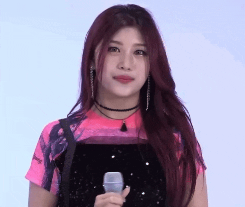 a woman with red hair is holding a microphone in her hand and wearing a choker .