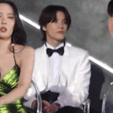 a man in a tuxedo is sitting next to a woman in a green dress and a man in a white suit .
