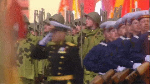 a group of soldiers marching in a line with a man in a black uniform