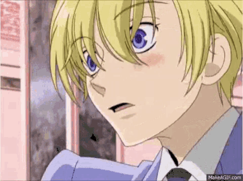 a close up of a blonde anime boy with blue eyes and a suit and tie .