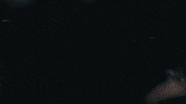 a woman in a white shirt is dancing in a dark room