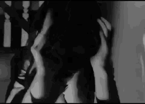 a black and white photo of a woman covering her face with her hands .