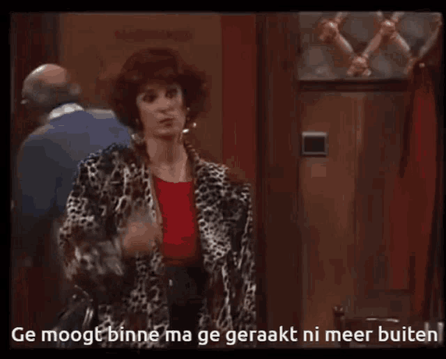 a woman in a leopard print jacket stands in front of a door with the words ge moopt binne ma ge geraakt ni meer buiten