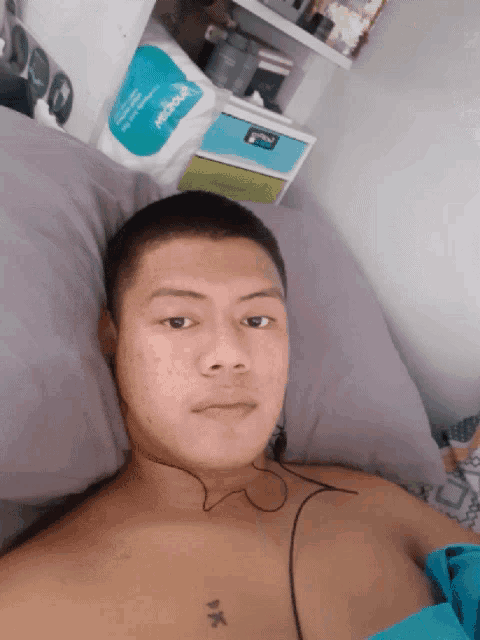 a man laying on a bed with a tattoo on his chest that says " pk "