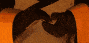 a close up of two people holding hands in front of an orange background .