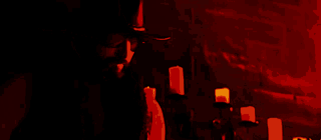 a man wearing a cowboy hat and glasses stands in front of candles