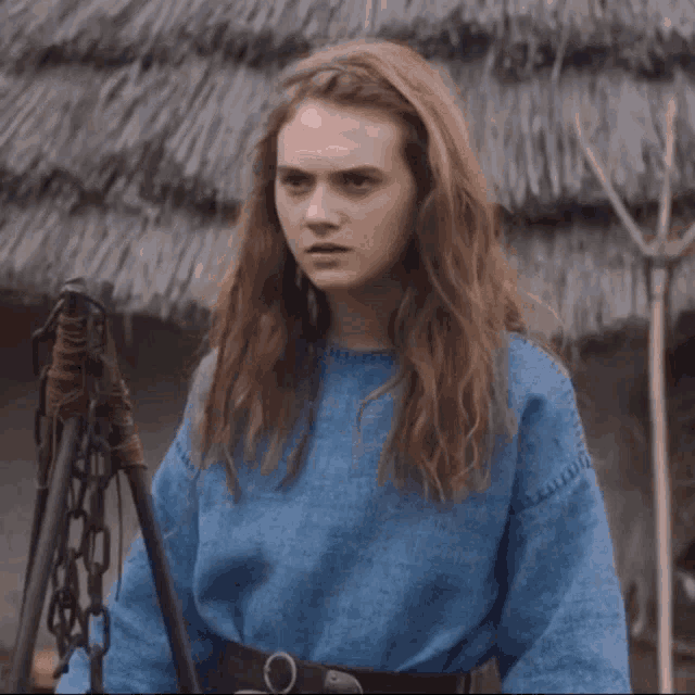 a woman in a blue sweater is looking up with her eyes closed .